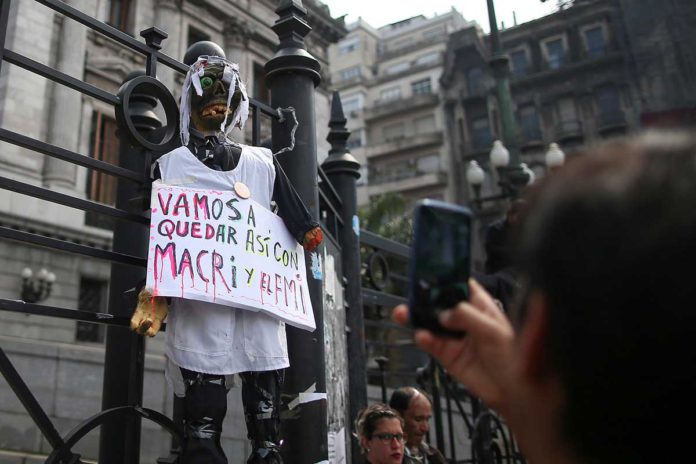 A demonstrator takes a picture of a puppet hanging from a fence of the National Congress during a national teachers strike, in Buenos Aires