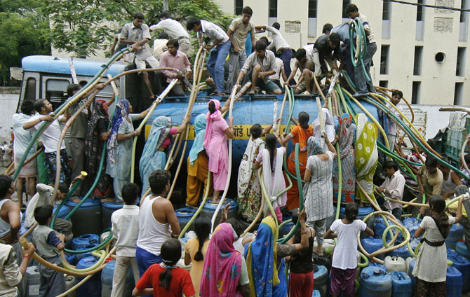Residents of Sanjay Colony, a residential neighbourhood, crowd around a water tanker provided by the state-run Delhi Jal (water) Board to fill their containers in New Delhi June 30, 2009. Delhi Chief Minister Sheila Dikshit has given directives to tackle the burgeoning water crisis caused by uneven distribution of water in the city according to local media. The board is responsible for supplying water in the capital. REUTERS/Adnan Abidi (INDIA ENVIRONMENT SOCIETY) INDIA